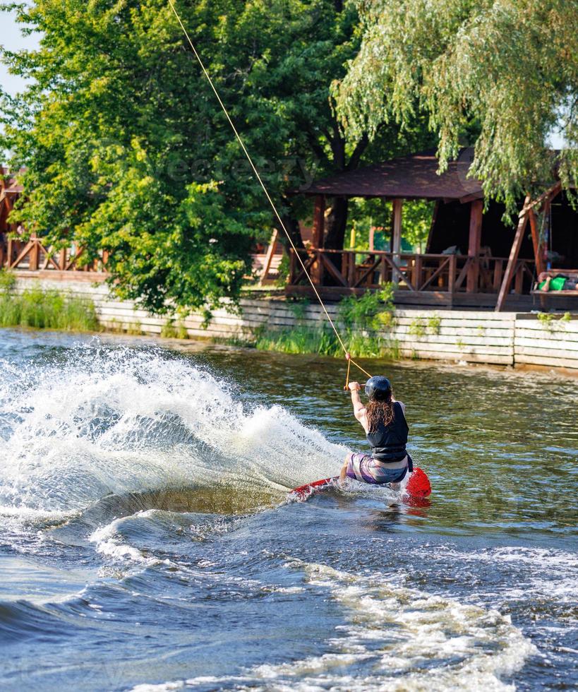 Steep turn of a wakeboarder on a water river surface in a sports park on a summer day. photo