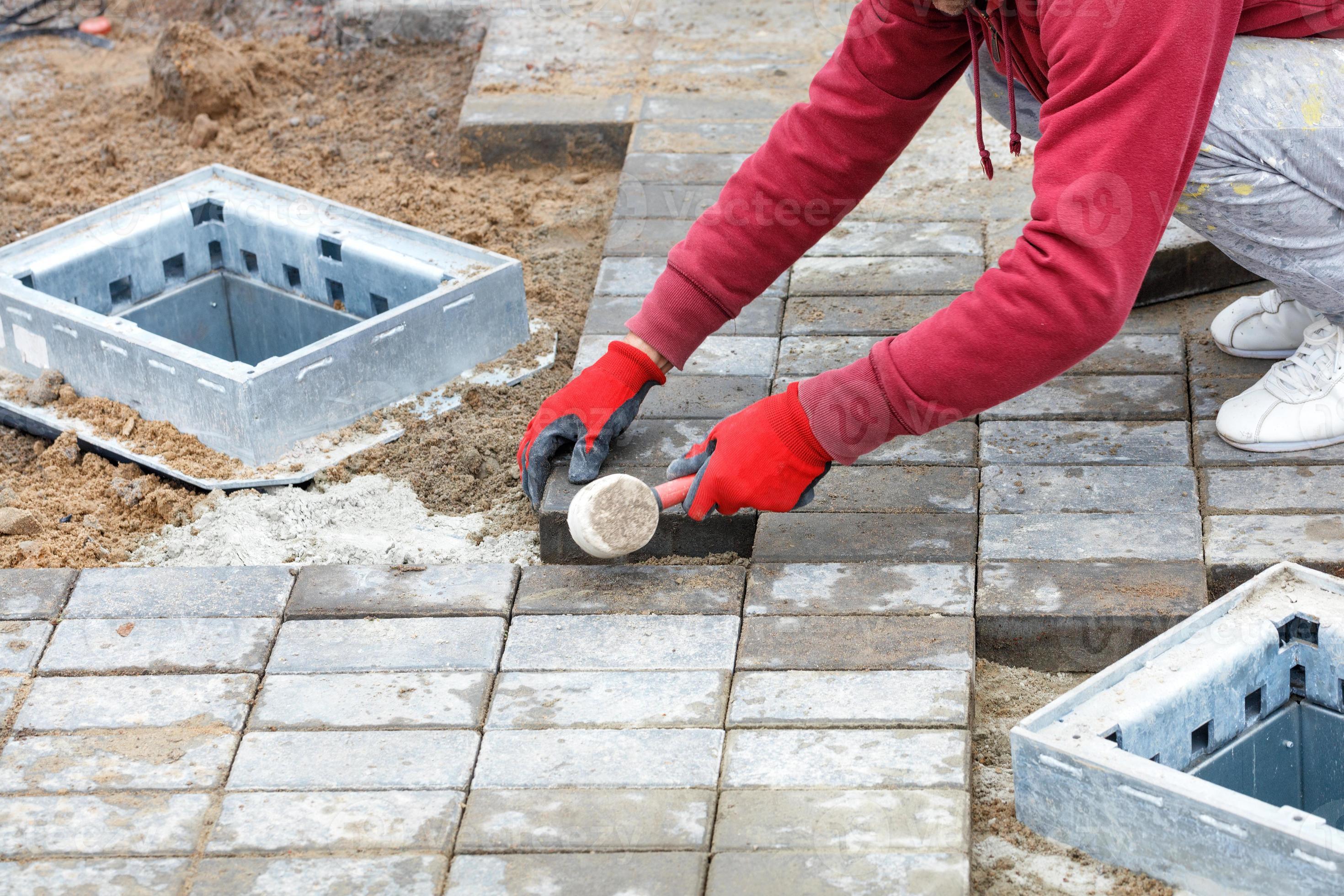 A worker lays paving slabs around storm drains. 11423151 Stock Photo at