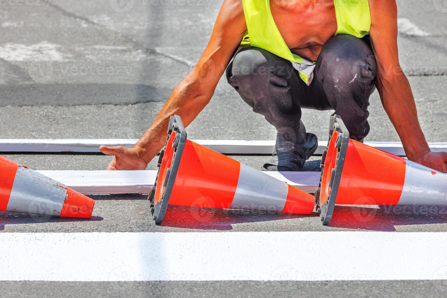 A road service worker moves a wooden template for the installation of fresh road markings for a pedestrian crossing. photo