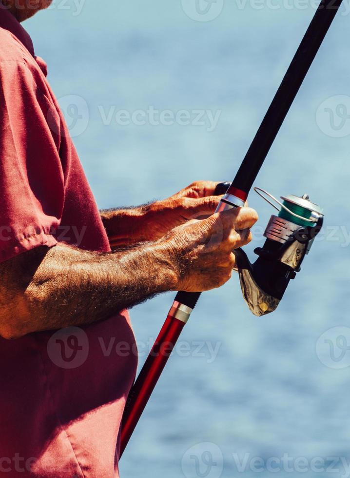 Fisherman hands holding fishing rod close up photo