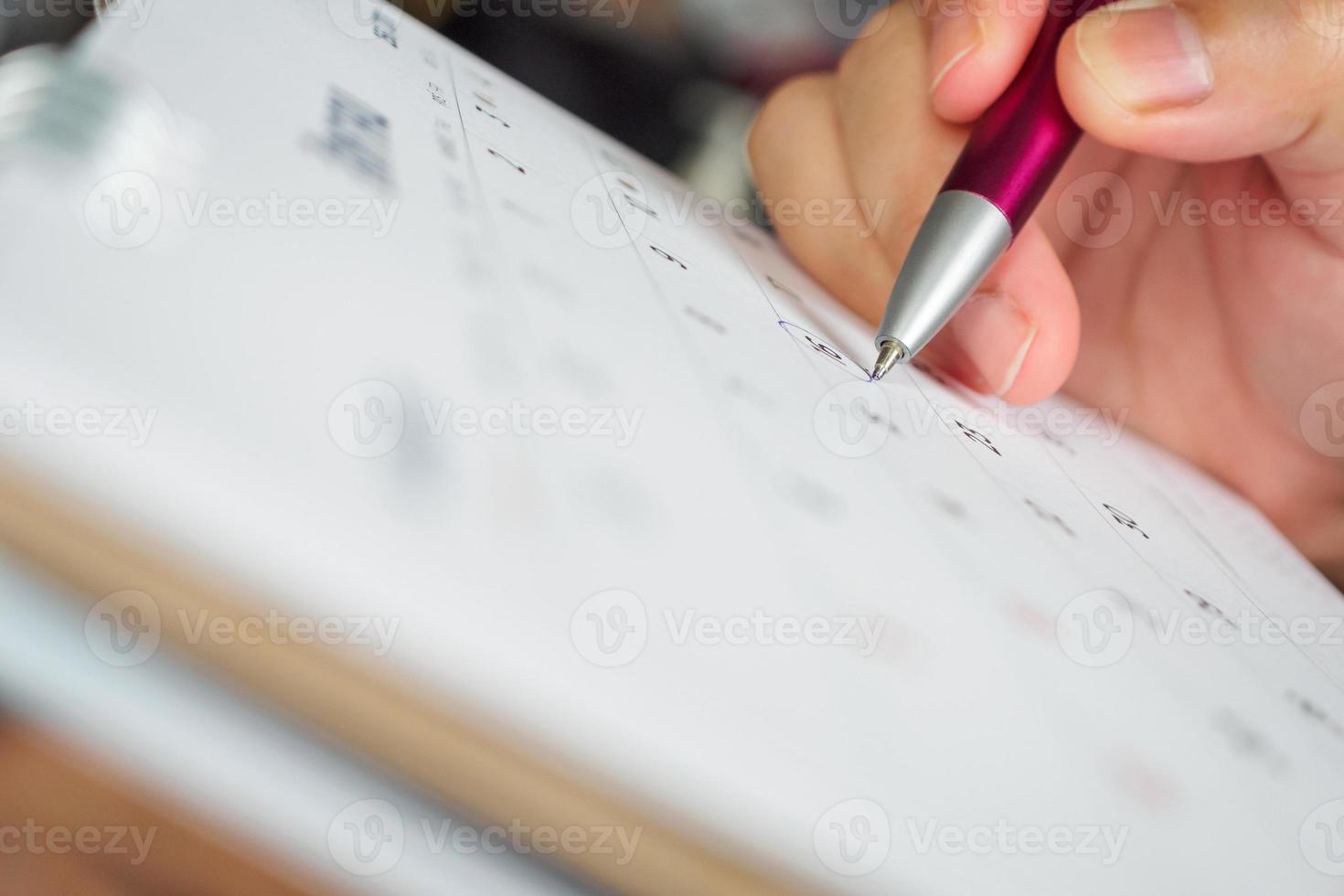 female hand holding pen circle mark on calendar page photo