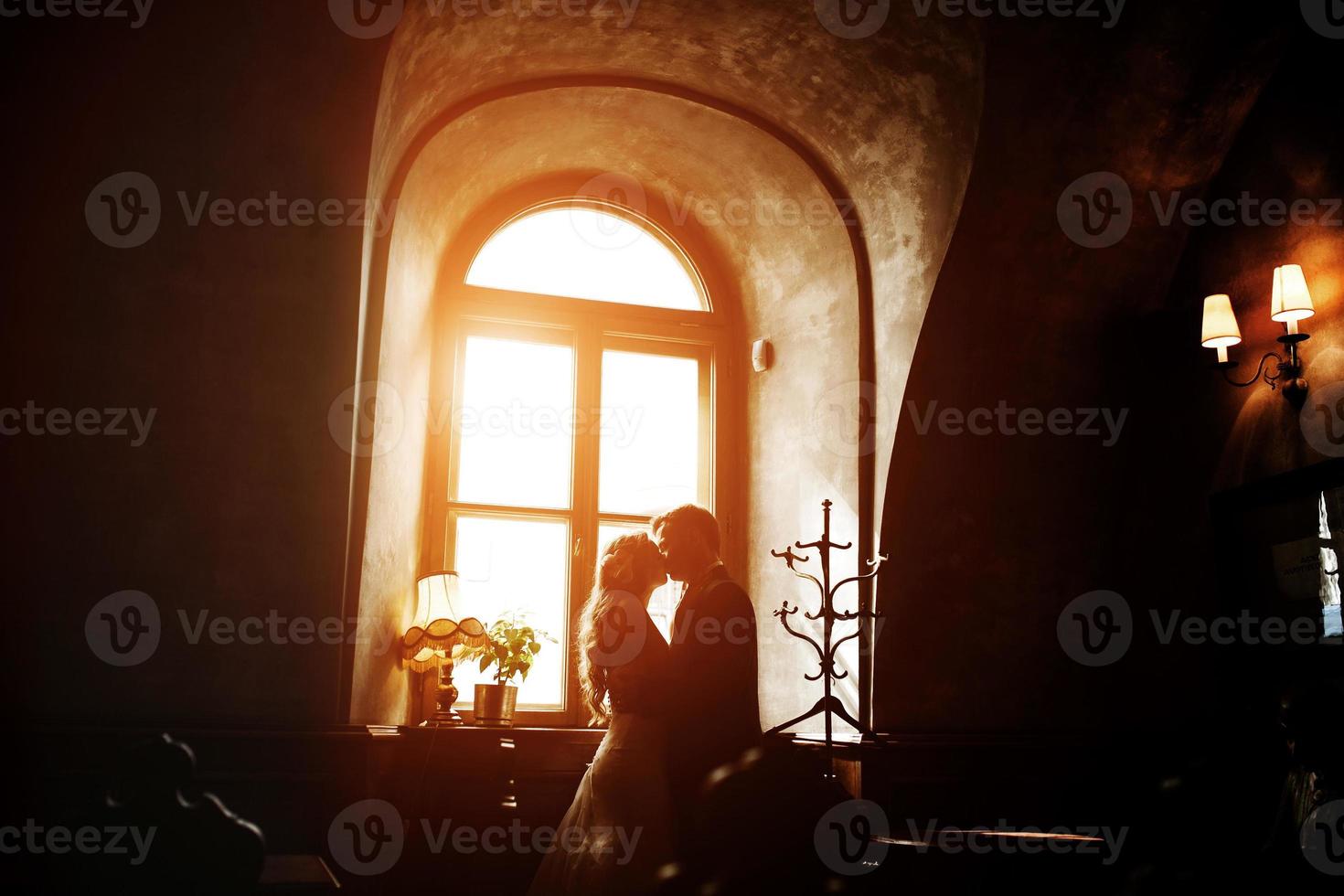 The bride and groom in a cozy house, photo taken with natural light from the window.