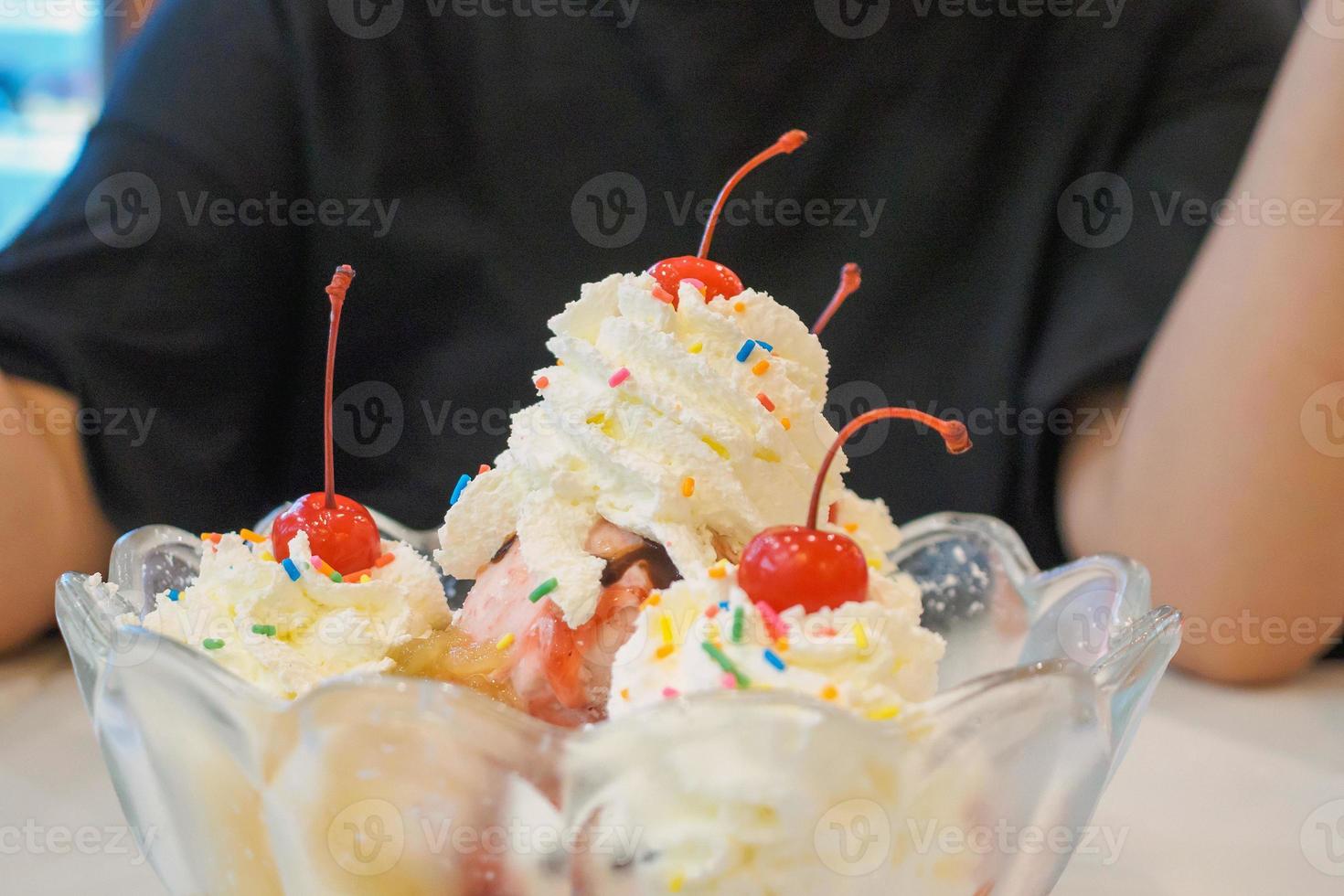 ice cream in glass bowl with whipped cream and red cherry on top photo
