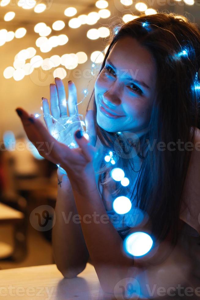 Woman holding glowing christmas garland in hands photo