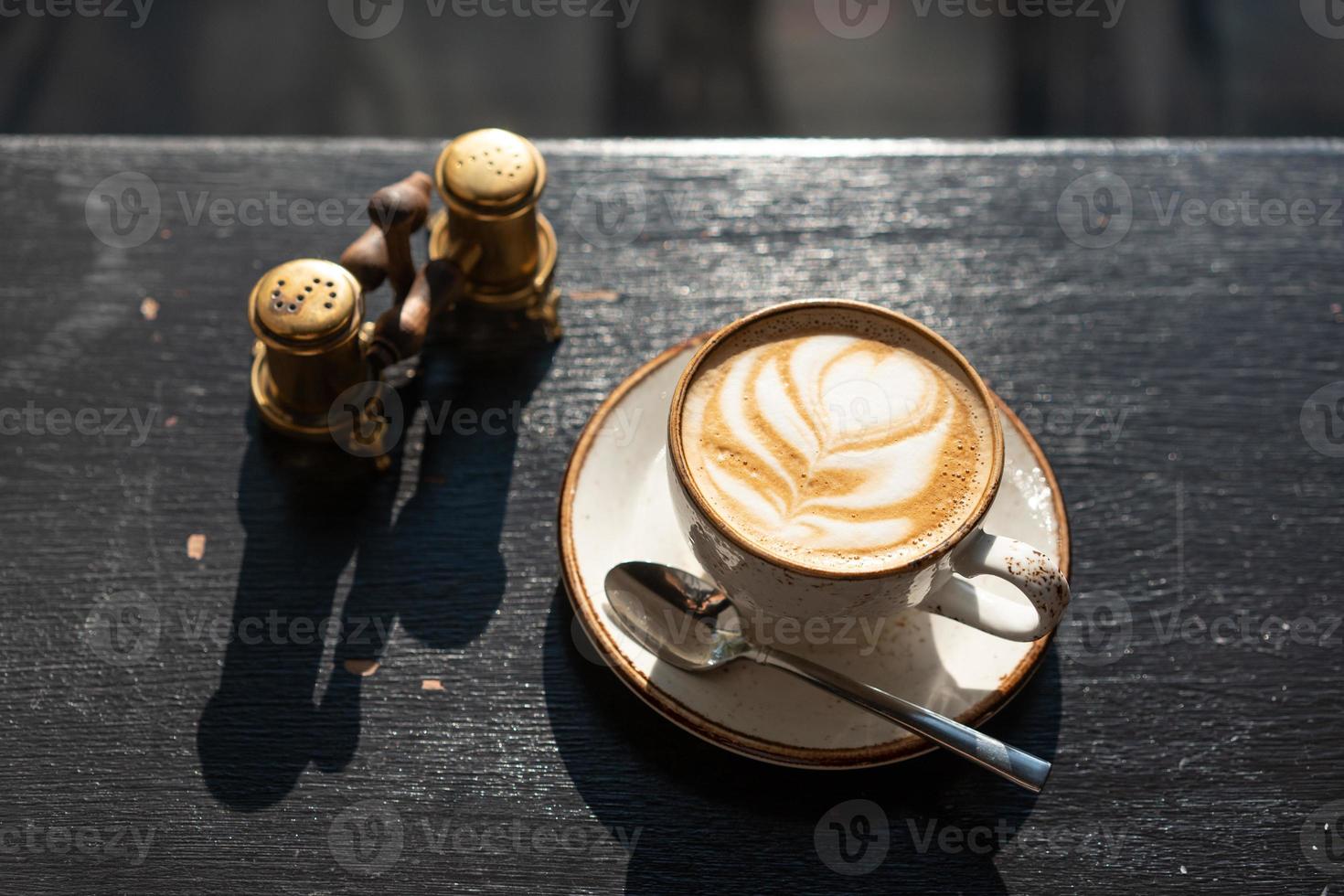 café de la cafetería en una taza blanca con un diseño de hoja foto