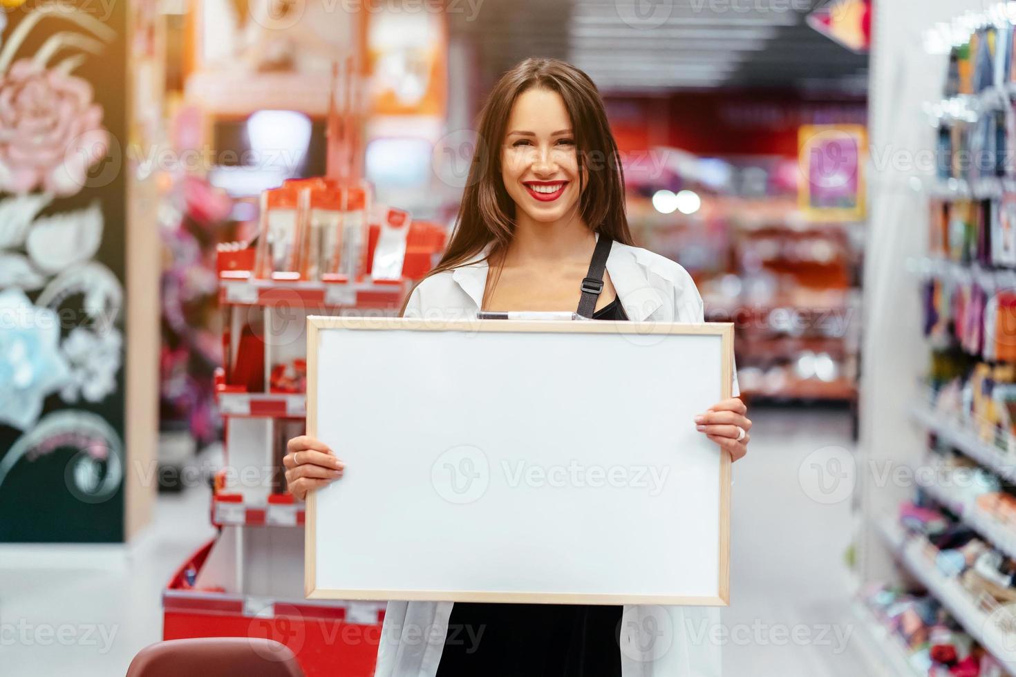 mujer morena sonriente sosteniendo tablero en blanco blanco foto