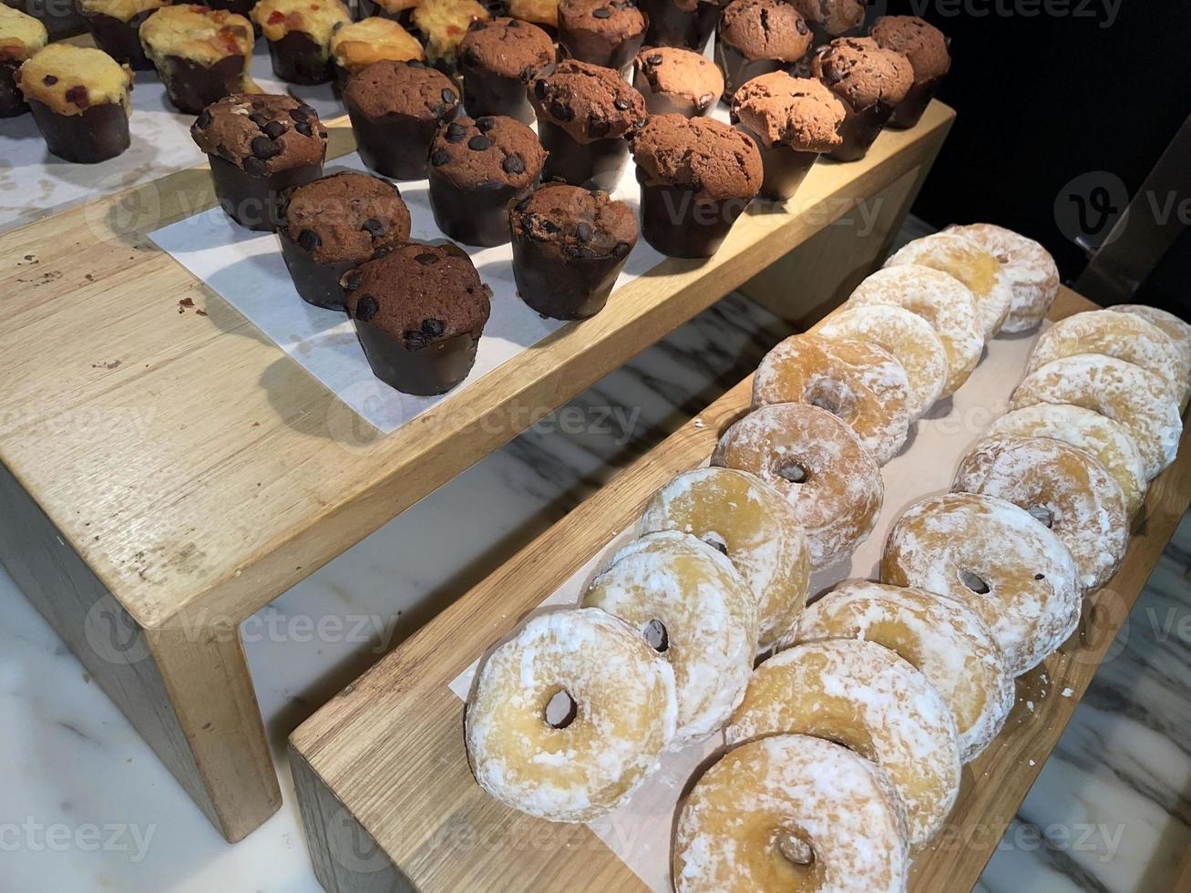 filas de deliciosos donuts frescos en la panadería, deliciosos donuts múltiples, donuts de enfoque selectivo foto
