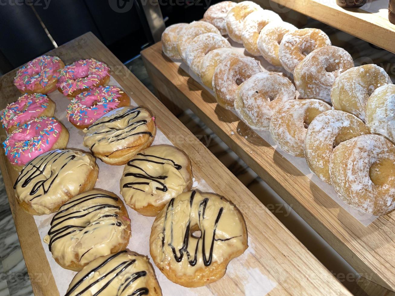 filas de deliciosos donuts frescos en la panadería, deliciosos donuts múltiples, donuts de enfoque selectivo foto