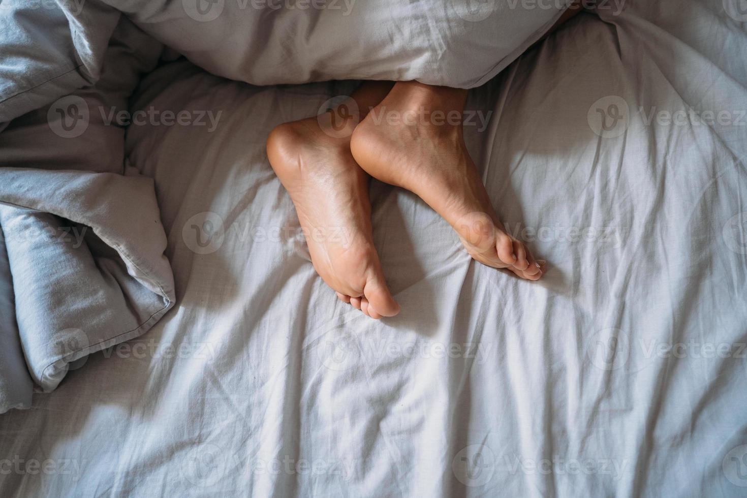 Close-up woman feet alone in white bed photo