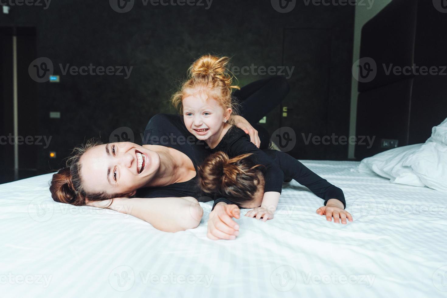 Mom and two daughters have fun on the bed photo