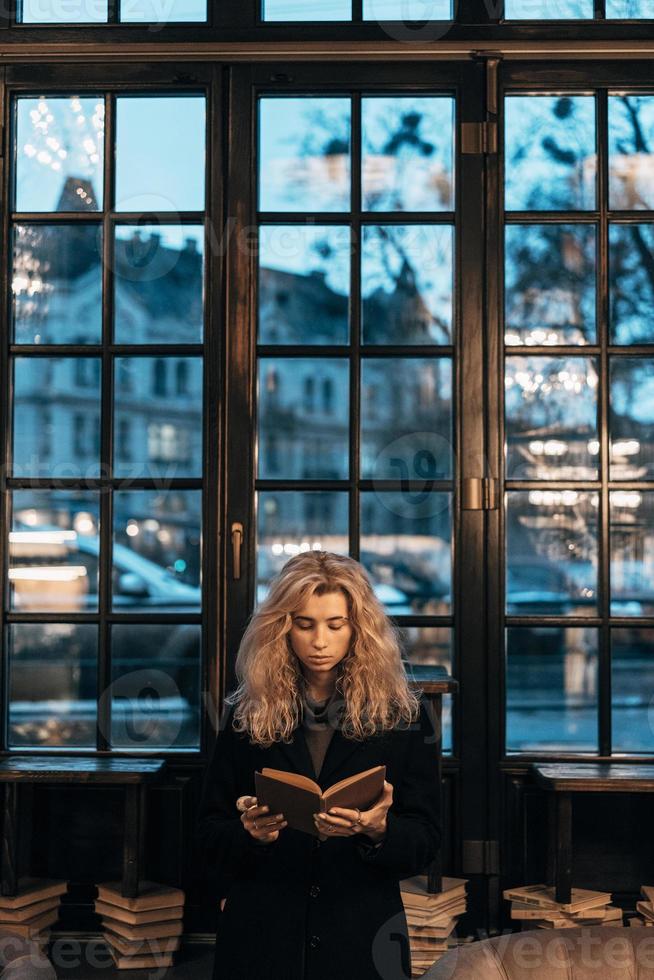 Woman reading a book on the background of window photo