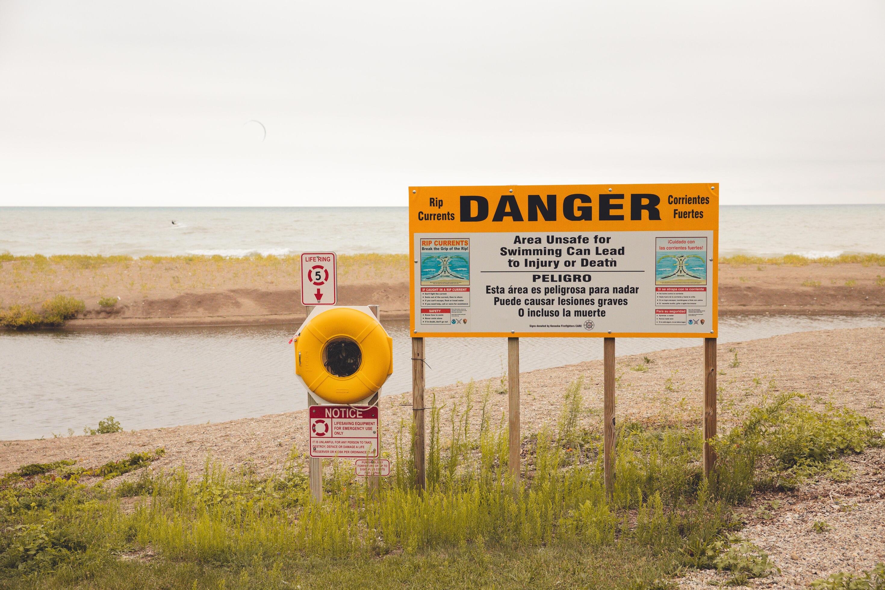 señal de peligro en la playa de arena del lago michigan. malas hierbas