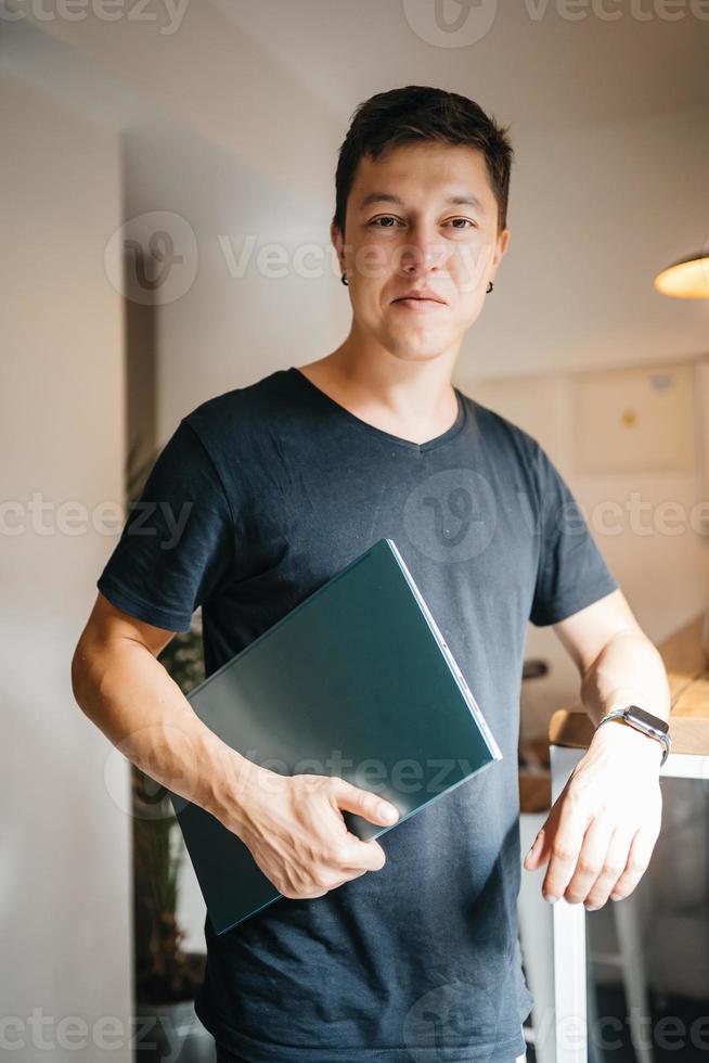 Guy with a closed laptop in hand, indoors photo