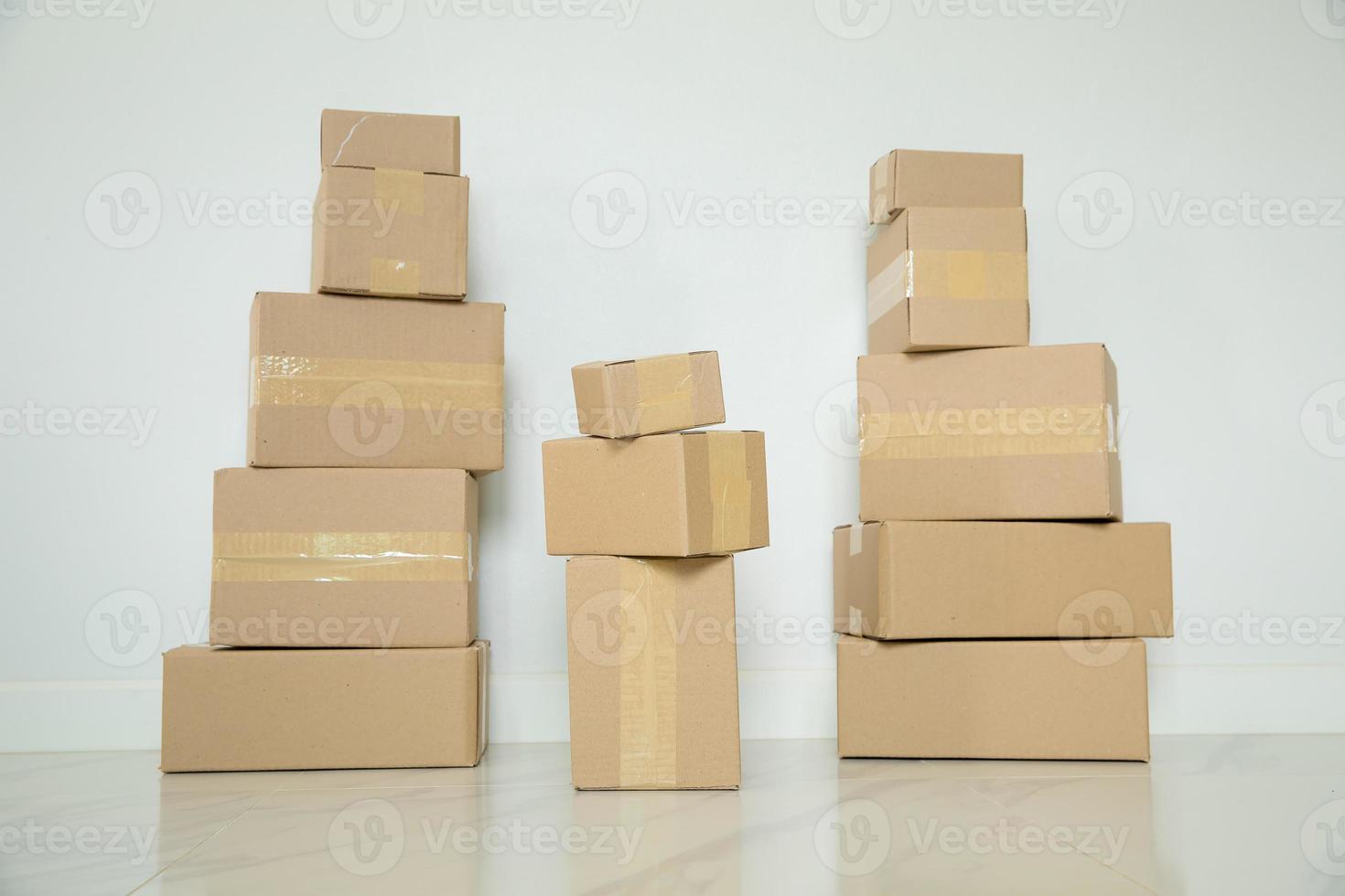 Stack of cardboard boxes for moving, Empty room with a white wall and cardboard boxes with unbranded barcode on the floor. Delivery of goods, shopping. Cardboard boxes on gray wall background. photo