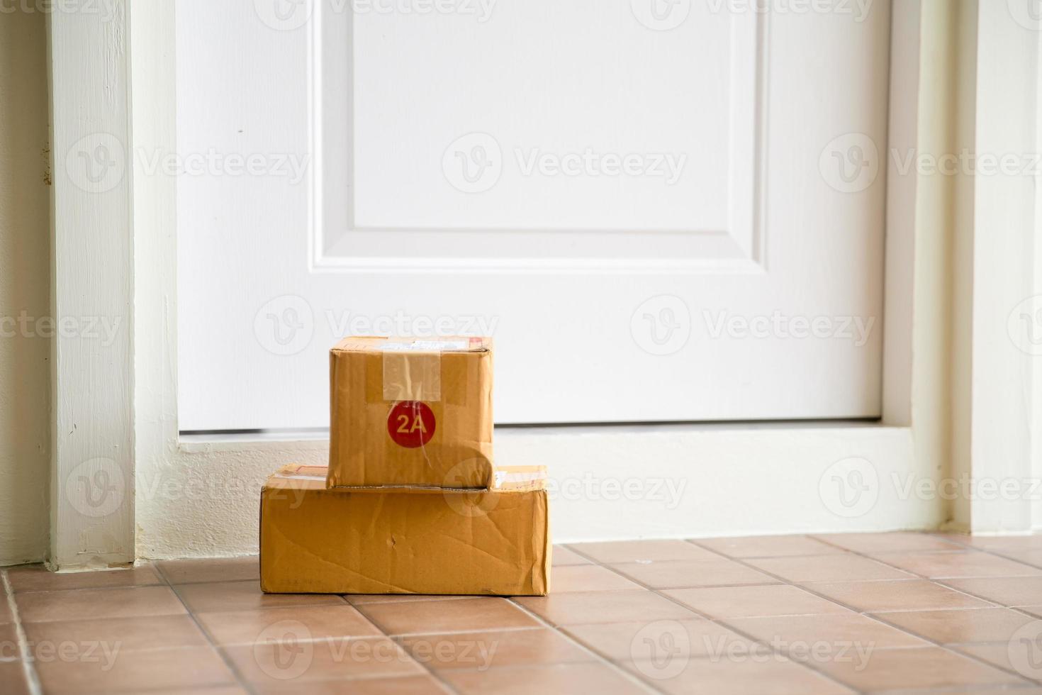 Cardboard parcel box near door on floor. Online shopping, boxes delivered to your front door. Easy to steal when nobody is home. Parcel in cardboard box on doorstep. Delivery service photo