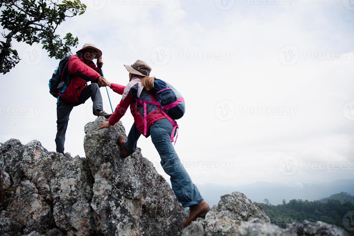 Person hike friends helping each other up a mountain. Man and woman giving a helping hand and active fit lifestyle. Asia couple hiking help each other. concept of friendship, teamwork. photo