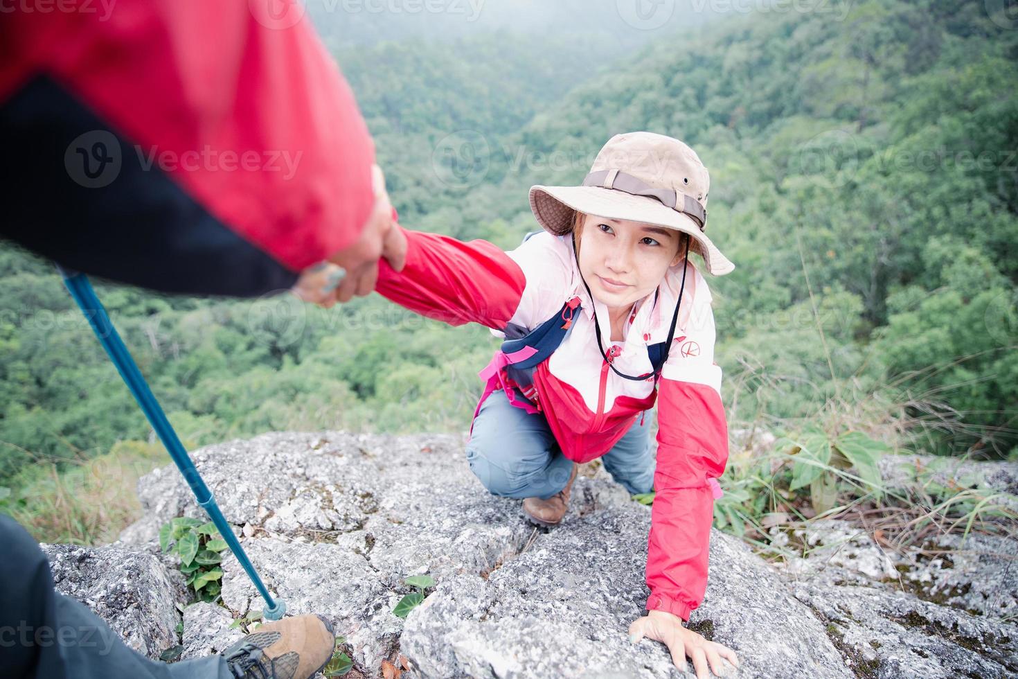Person hike friends helping each other up a mountain. Man and woman giving a helping hand and active fit lifestyle. Asia couple hiking help each other. concept of friendship, teamwork. photo