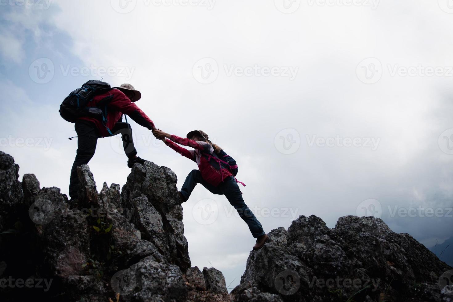 Person hike friends helping each other up a mountain. Man and woman giving a helping hand and active fit lifestyle. Asia couple hiking help each other. concept of friendship, teamwork. photo