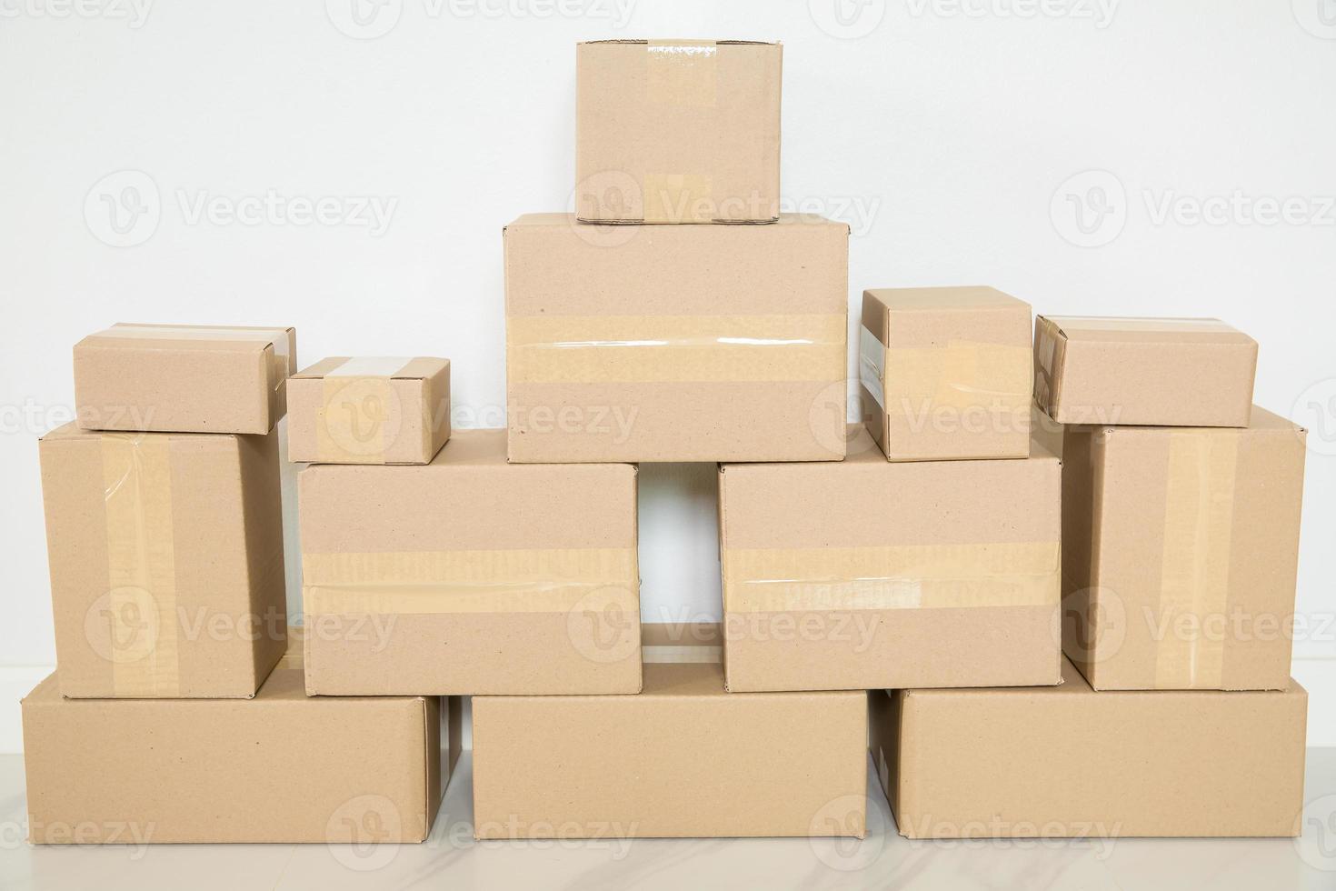 Stack of cardboard boxes for moving, Empty room with a white wall and cardboard boxes with unbranded barcode on the floor. Delivery of goods, shopping. Cardboard boxes on gray wall background. photo