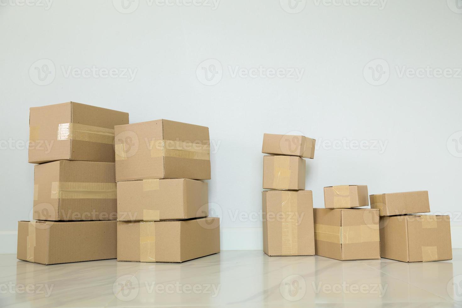 pila de cajas de cartón para mudanzas, habitación vacía con una pared blanca y cajas de cartón con código de barras sin marca en el suelo. entrega de mercancías, compras. cajas de cartón sobre fondo de pared gris. foto