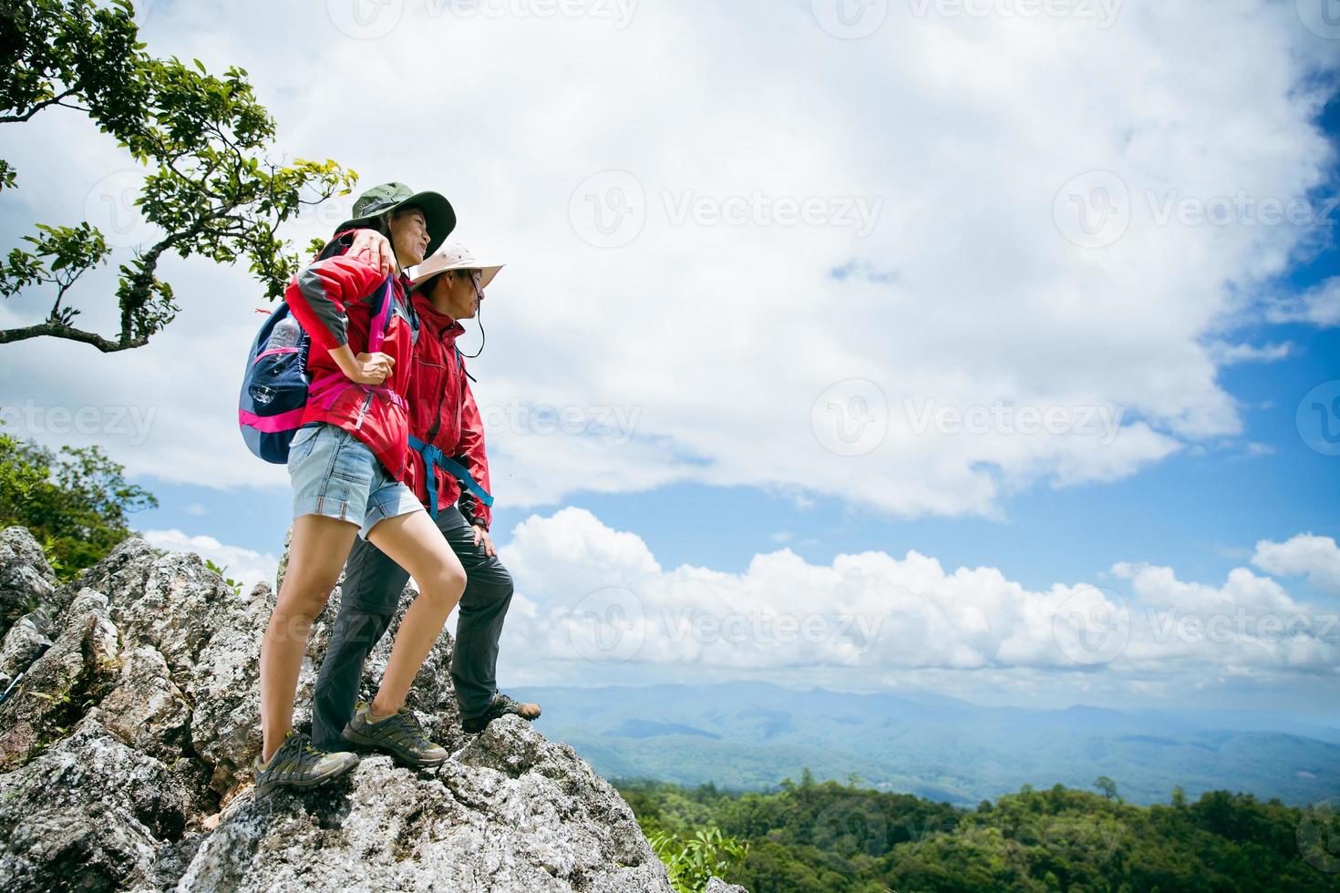 Young tourist couple watching spectacular mountain scenery in high mountains. man and woman hiker on top rock. A couple of travelers in love. People greet the dawn. Lovers travel. Copy space photo