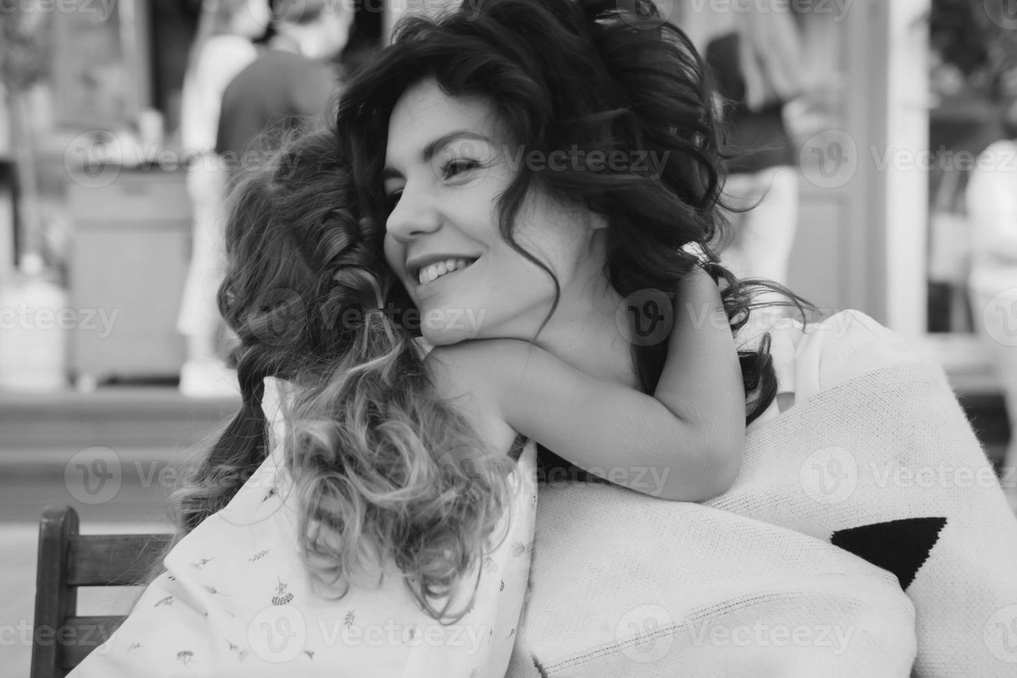 Cute little girl and her beautiful young mom hug each other photo