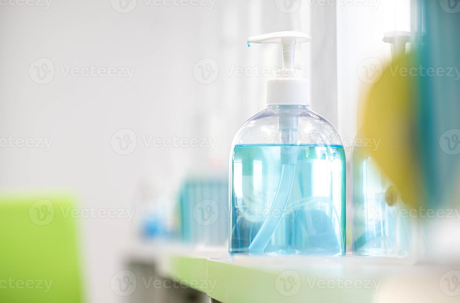 botella de gel de alcohol azul colocada sobre la mesa para atender a los clientes dentro de un banco, medidas para prevenir la propagación de enfermedades virales respiratorias foto
