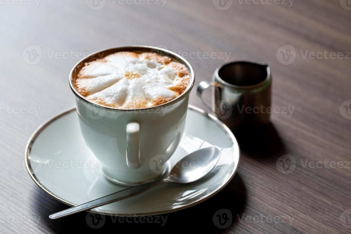 Close up of Coffee latte in the coffee mug and spoon on moder wooden table photo