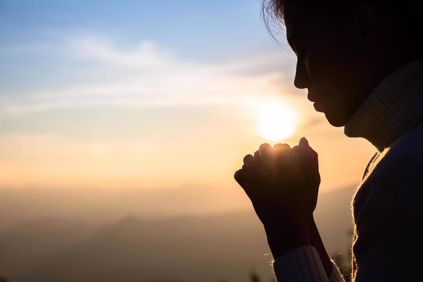 Woman praying in the morning on the sunrise background. Christianity concept. Pray background. Faith hope love concept. photo