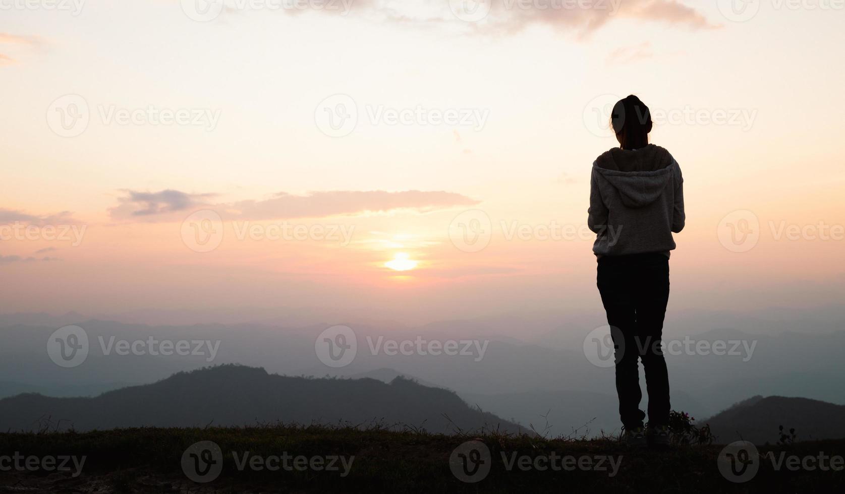 Silhouette of a woman praying outside at beautiful landscape at the top of the mountain, Copy space of man rise hand up on top of mountain and sunset sky abstract background. photo