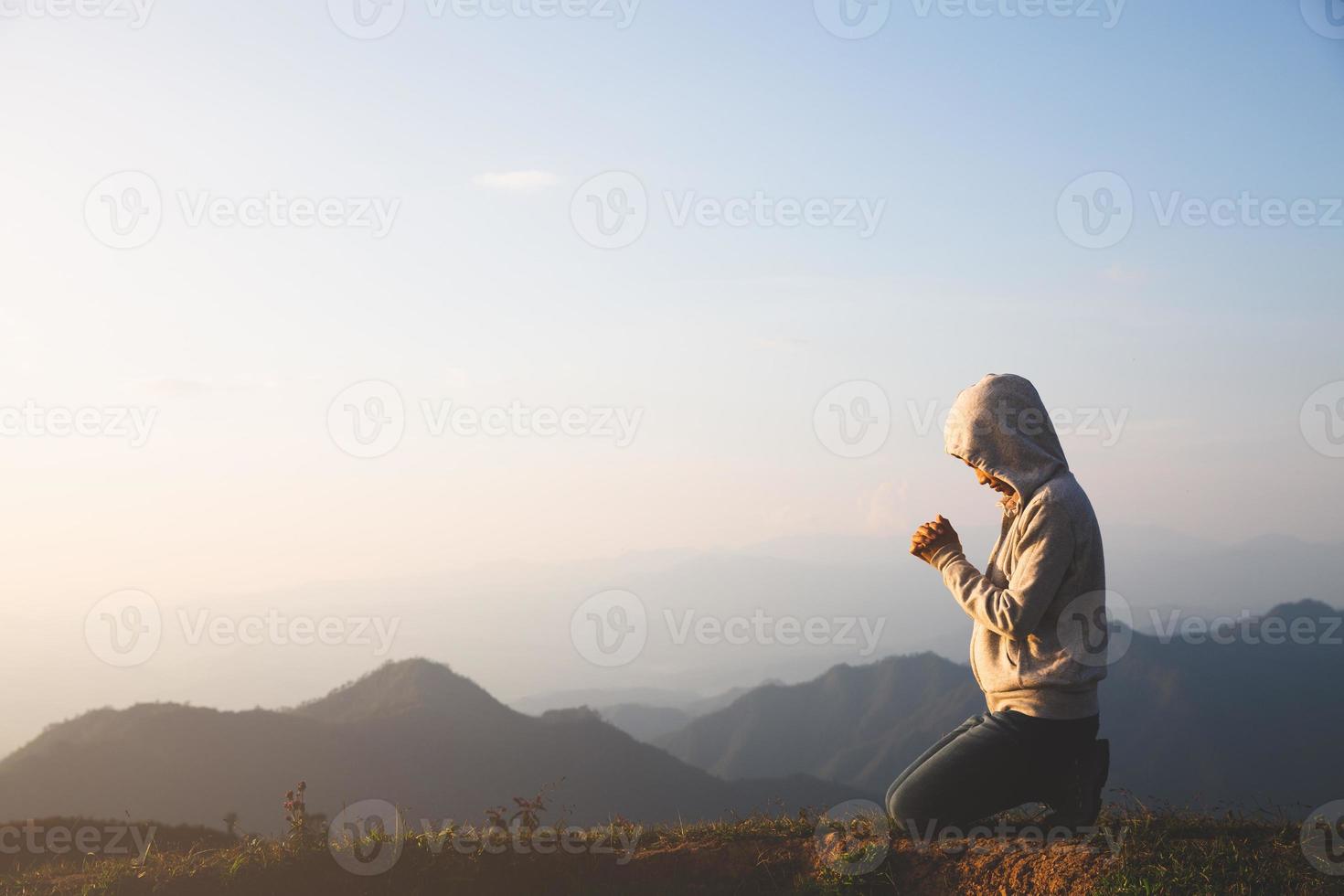 una mujer está rezando a dios en la montaña. orando las manos con fe en la religión y la creencia en dios en el fondo de bendición. poder de la esperanza o el amor y la devoción. foto