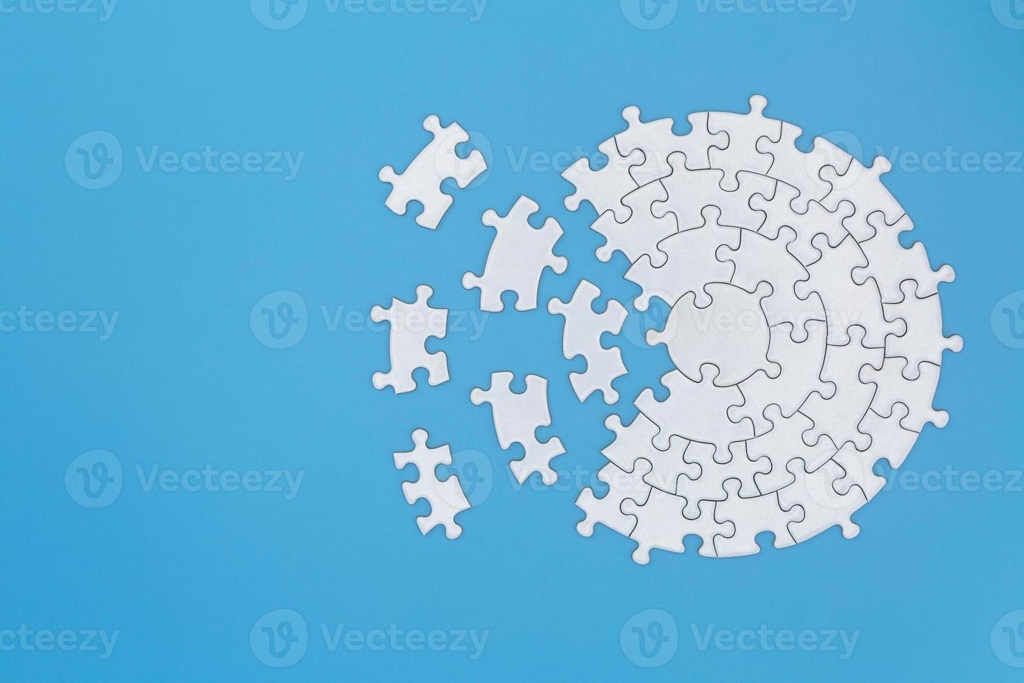 Unfinished white jigsaw puzzle pieces on blue background,  Copy space. photo