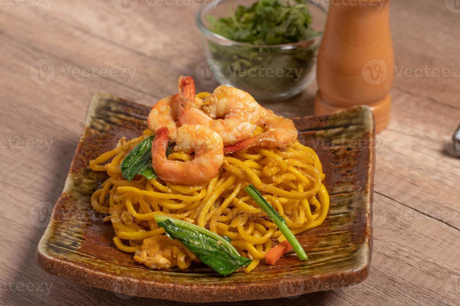 Fried noodles with shrimp in a plate on the table photo