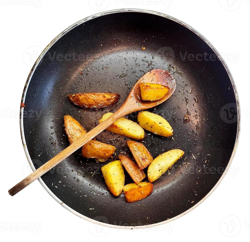 Cooking traditional village food. Fried potatoes in frying pan and wooden spoon. photo