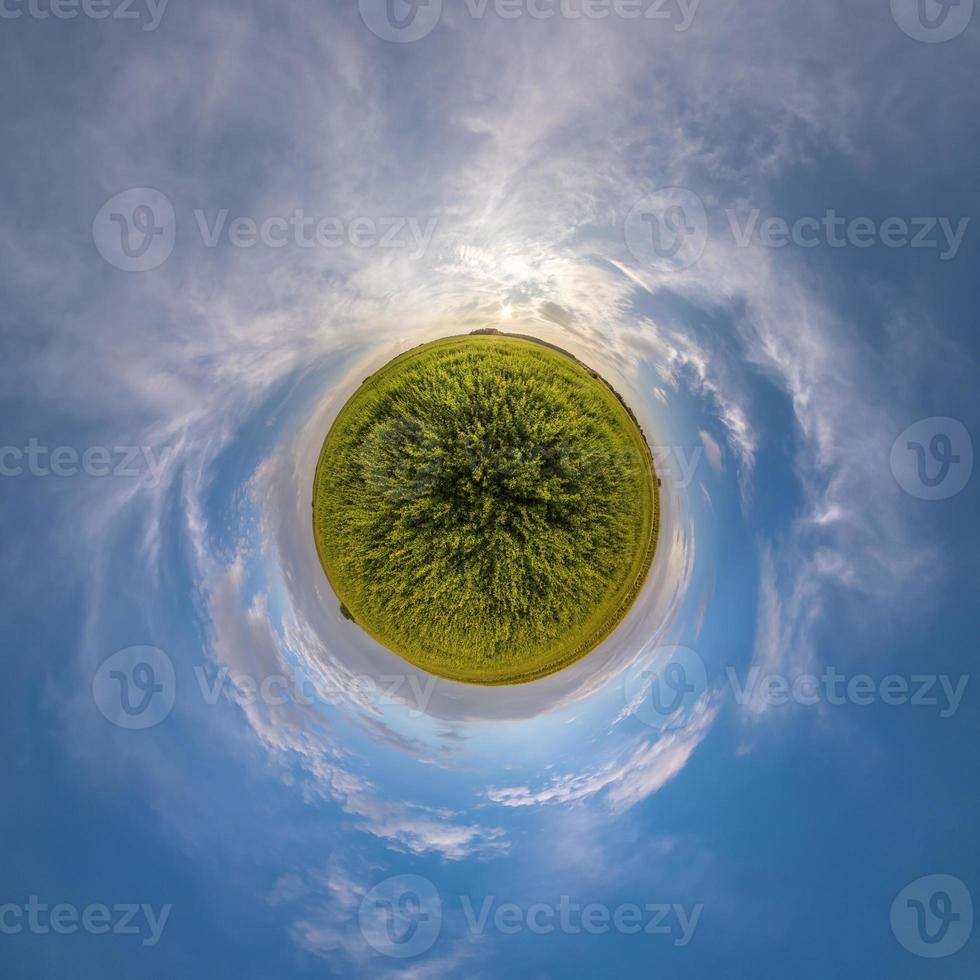 green tiny planet in blue sky with beautiful clouds. Transformation of spherical panorama 360 degrees. Spherical abstract aerial view. Curvature of space. photo