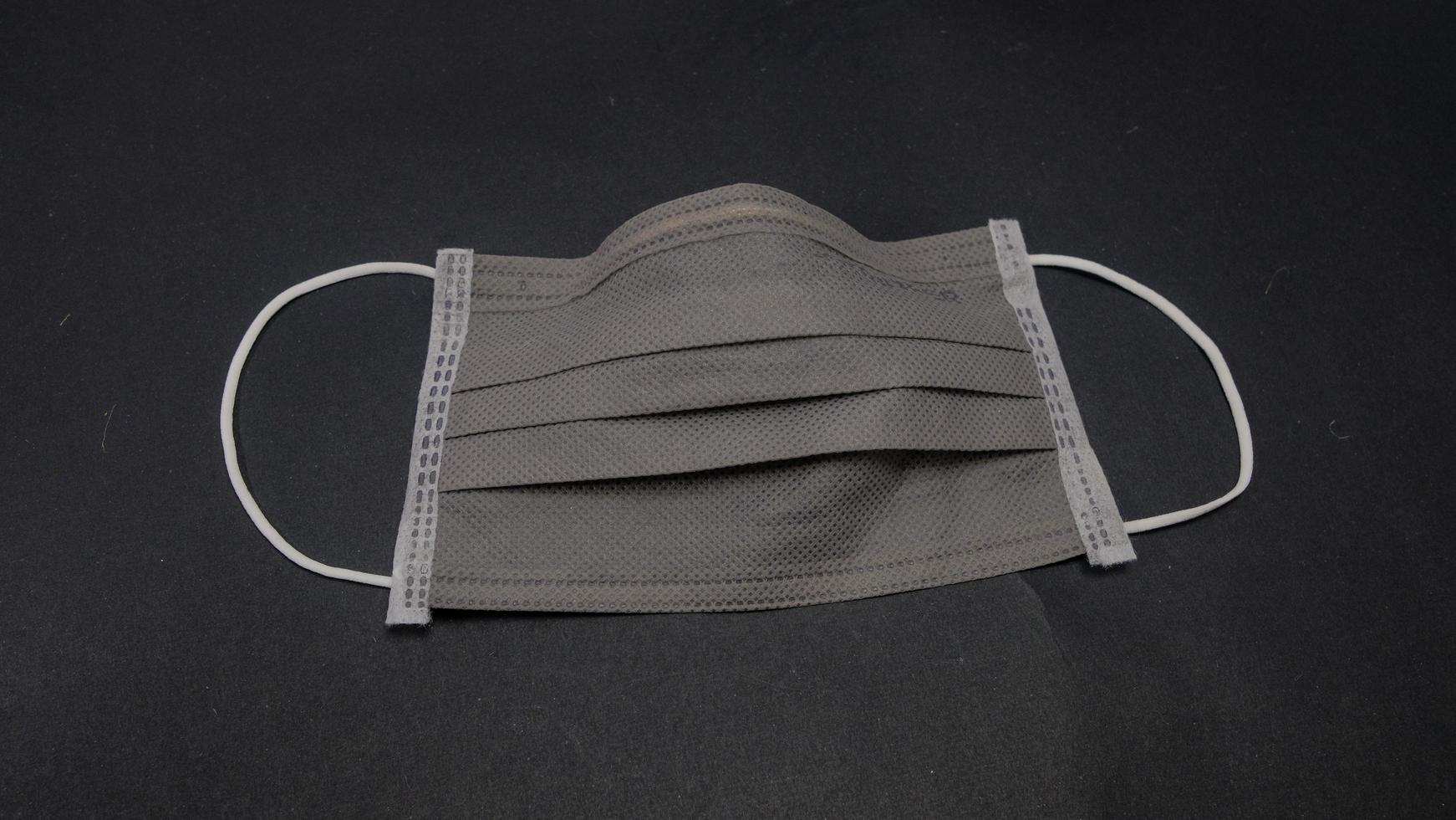 Used surgical face mask on black background. Dirty and many disease. Should be destroy and separating before throw it in bin. Cannot reuse. Health care concept. Copy space. photo