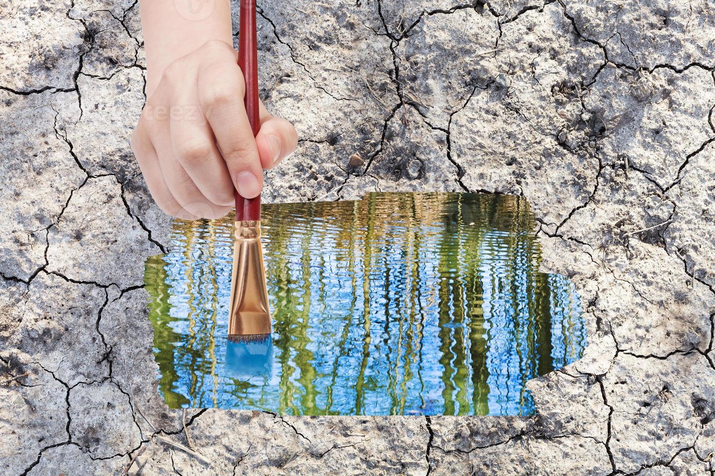 paintbrush paints water puddle on dried earth photo