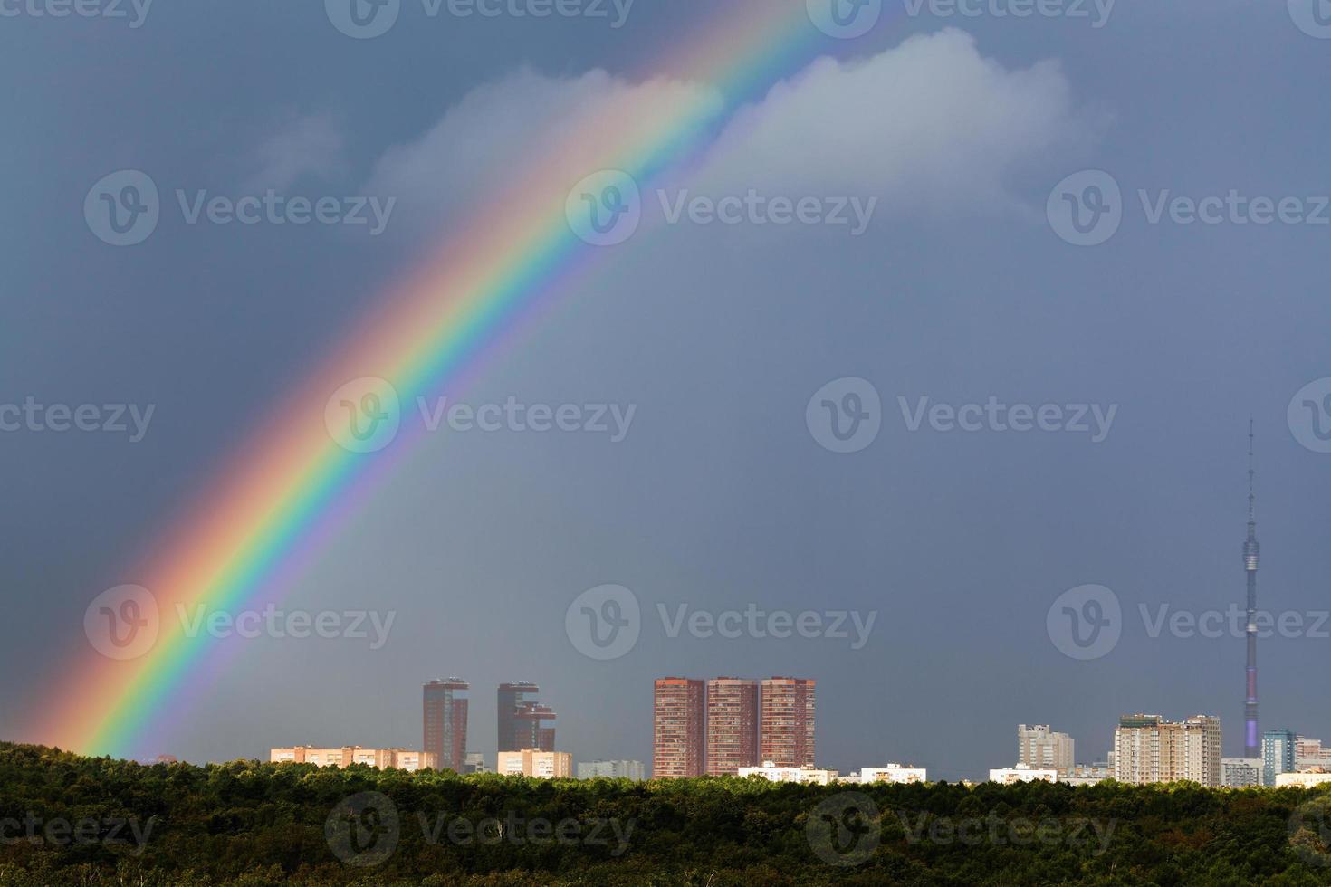 arco iris en el cielo gris sobre la ciudad con torre de televisión foto