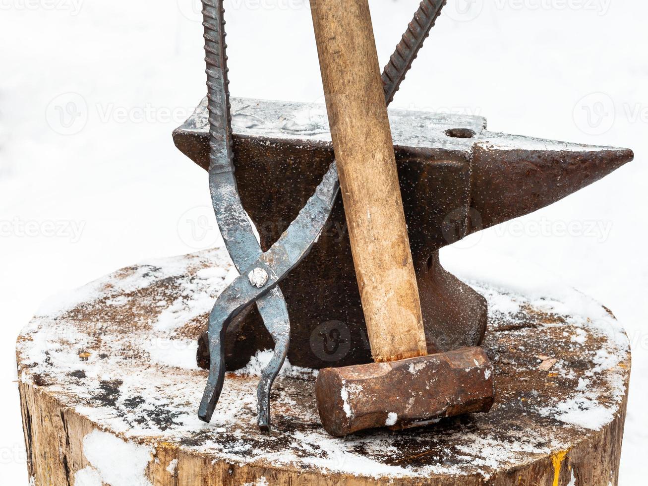 anvil, blacksmith tongs and hammer in smithy photo