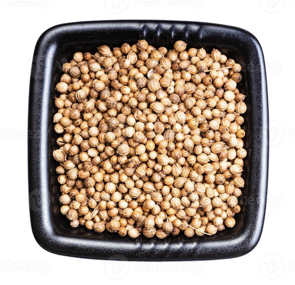 dried coriander seeds in black bowl isolated photo
