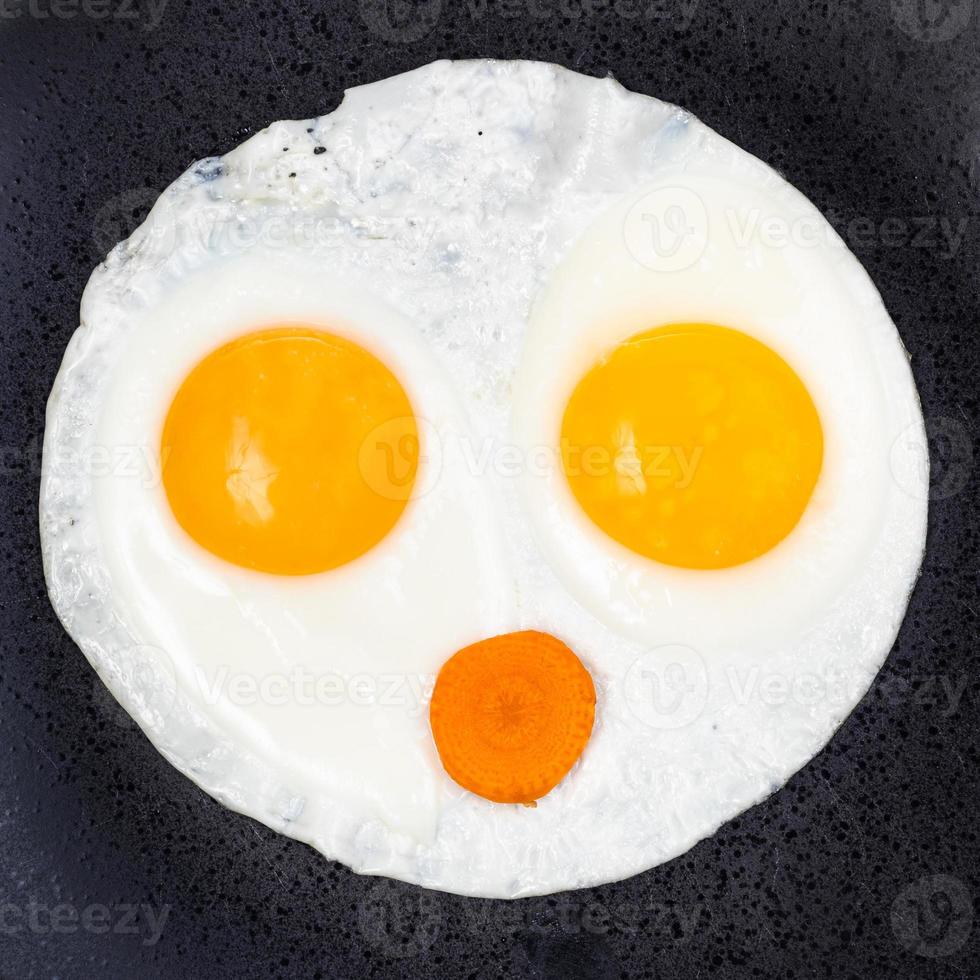fried eggs and slice of carrot on plate close up photo