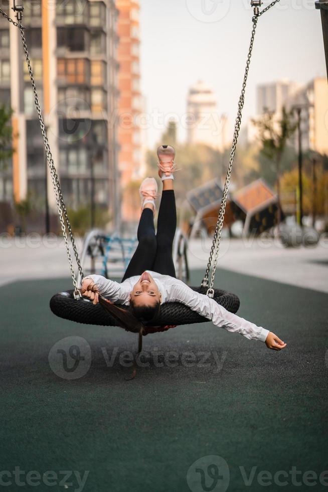 Young woman rides on a swing at the playground. photo