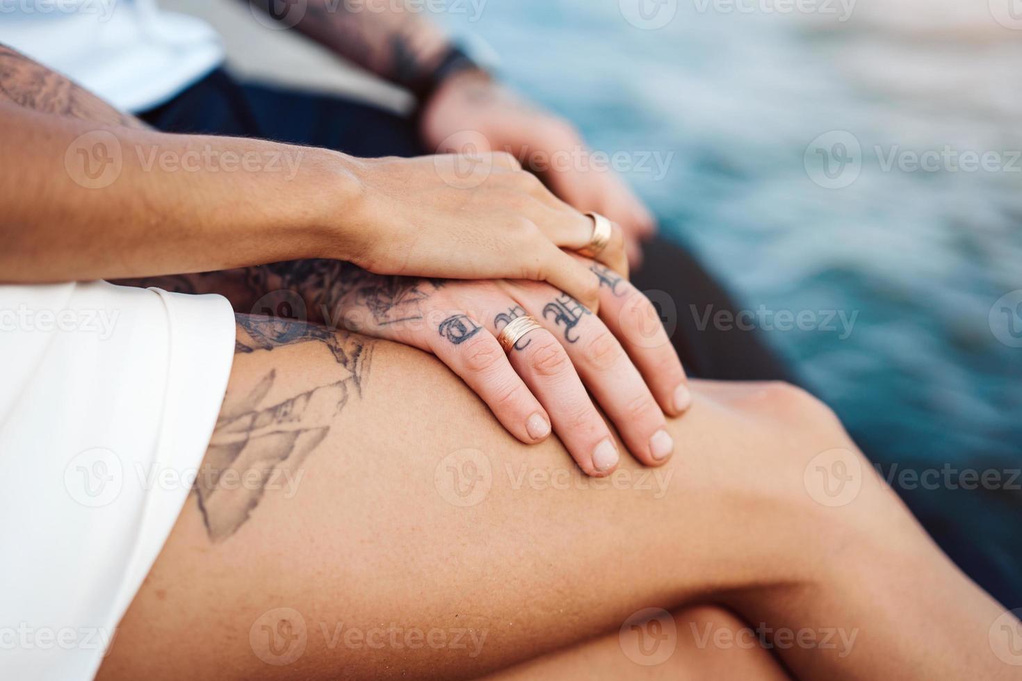 una pareja joven está sentada en el muelle junto al mar foto