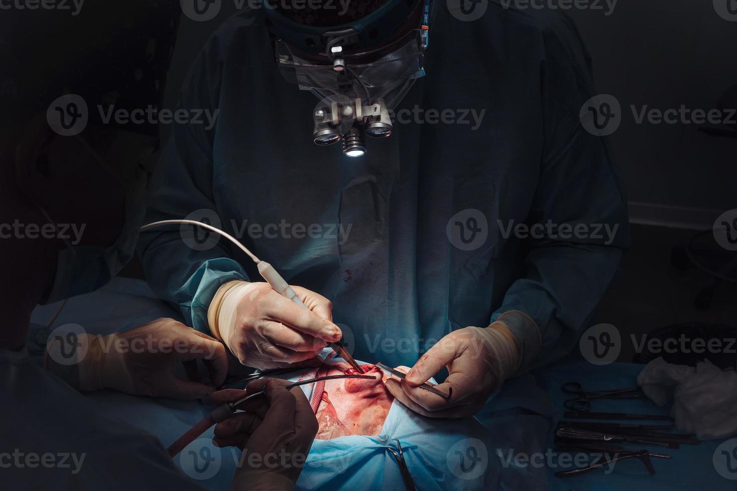 Surgeon and his assistant performing cosmetic surgery on nose photo