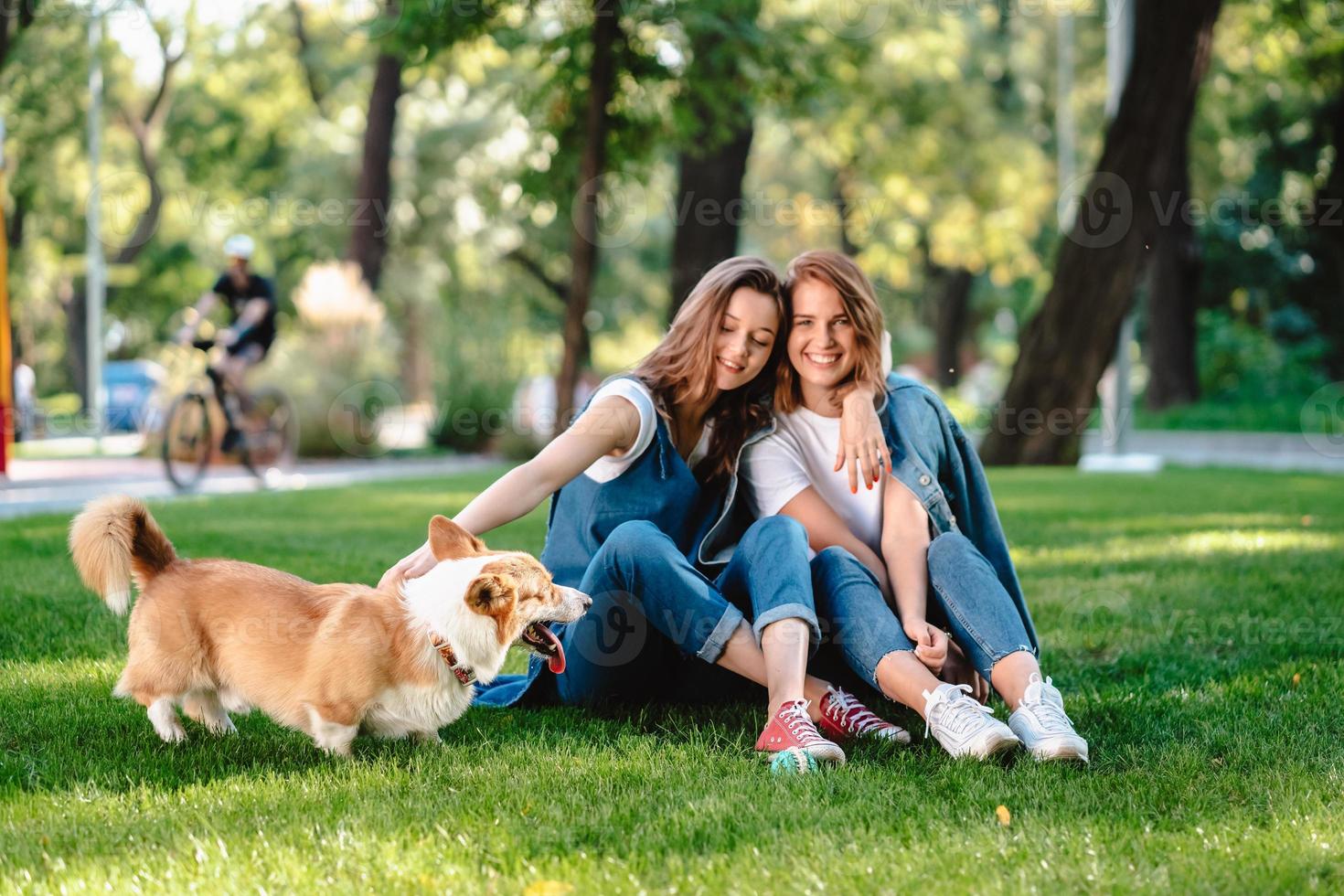 dos amigas en el parque juegan con un perrito foto