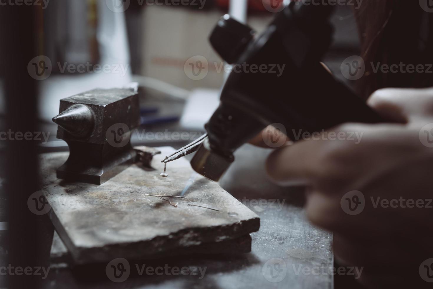 In the workshop, a woman jeweler is busy soldering jewelry photo