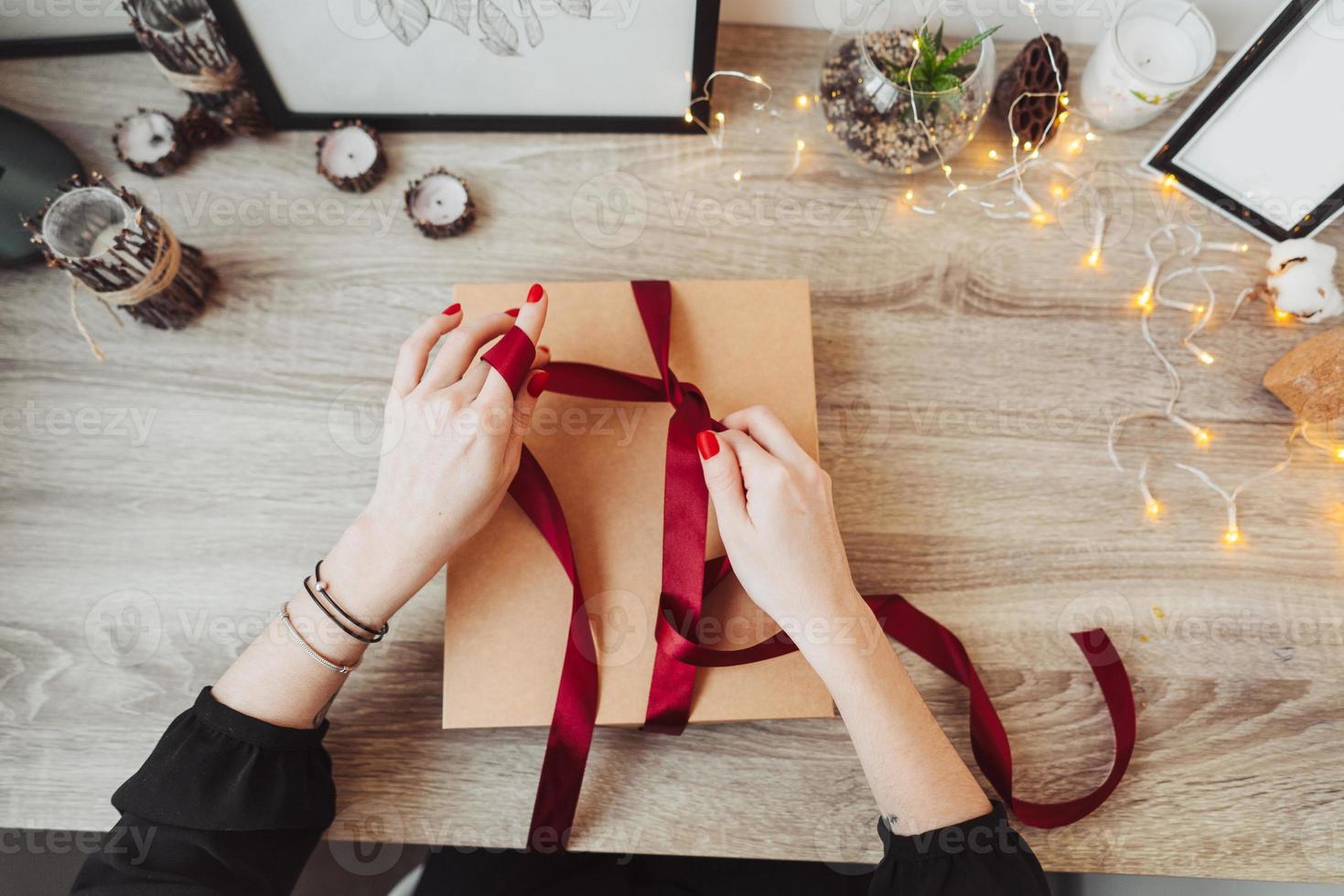 Woman wrapping present in paper with red ribbon. photo