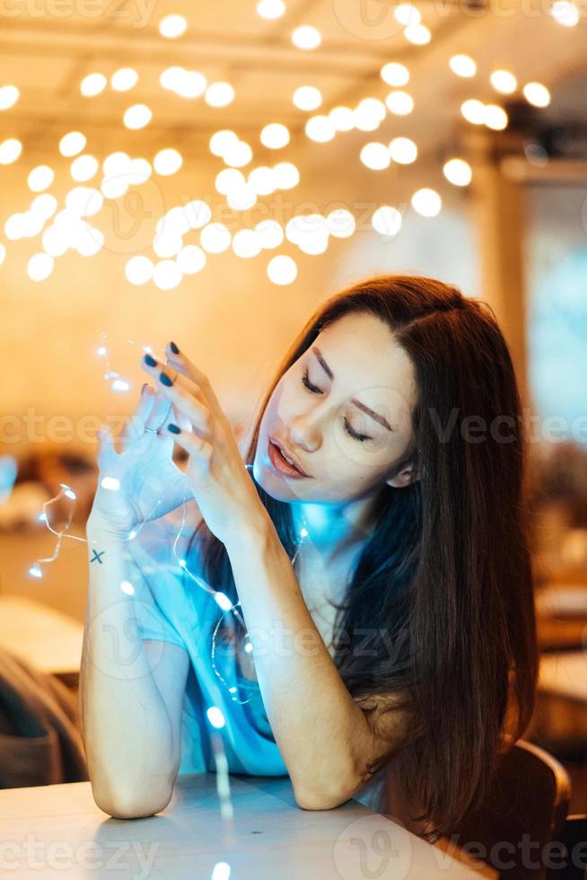 mujer sosteniendo una guirnalda navideña brillante en las manos foto