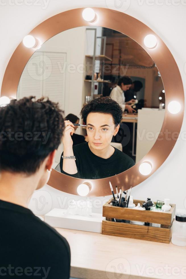 Attractive woman at the mirror in beauty studio photo