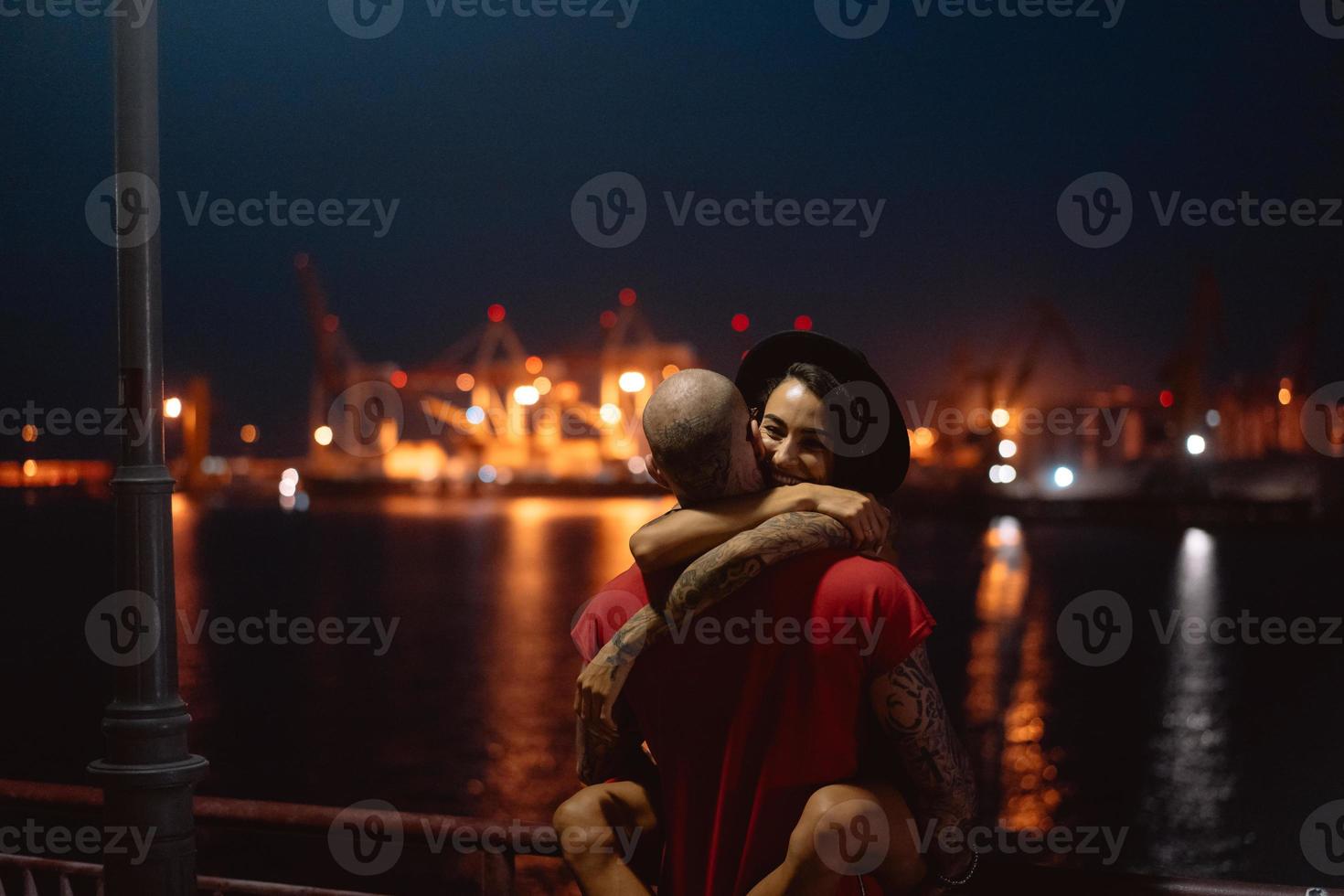 Guy and girl hugging each other on a background of the night port photo